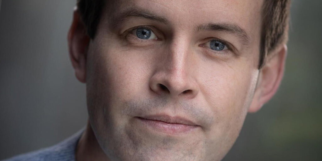 Portrait of Daniel Smales, close-up shot with a neutral expression, light eyes, and short brown hair.